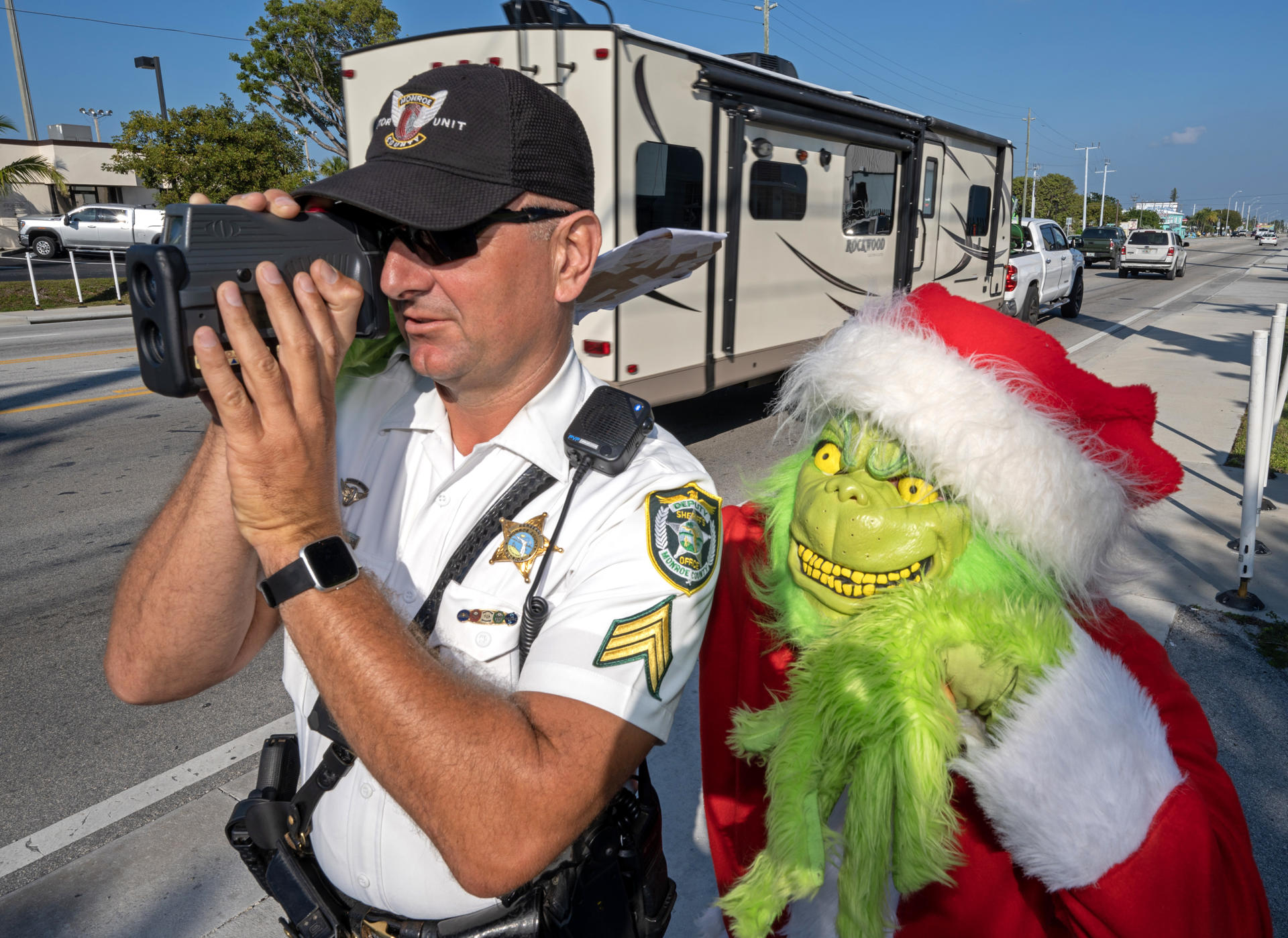 Fotografía cedida por la Oficina de noticias de los Cayos de Florida donde aparece el coronel de la oficina del alguacil del condado de Monroe, Lou Caputo, disfrazado de Grinch, y el diputado Andrew Leird mientras miden la velocidad de conductores en la autopista Florida Keys Overseas hoy, en Marathon, Florida (Estados Unidos). EFE/ Andy Newman /Florida Keys News Bureau/ SOLO USO EDITORIAL/ SOLO DISPONIBLE PARA ILUSTRAR LA NOTICIA QUE ACOMPAÑA (CRÉDITO OBLIGATORIO)
