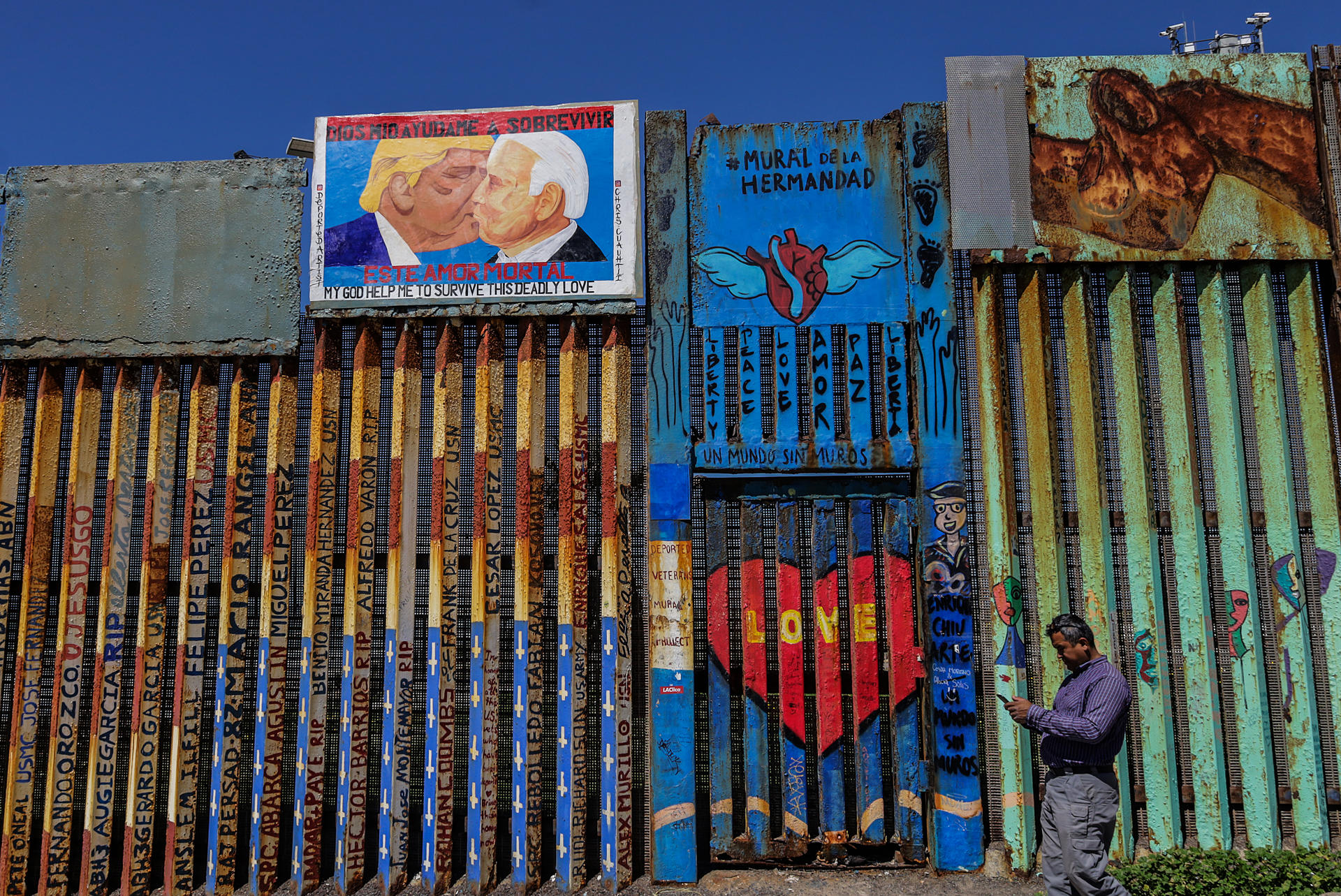 Vista de una imagen del expresidente estadounidense Donald Trump besando al actual mandatario, Joe Biden (d), el 28 de marzo de 2023 en el muro fronterizo en la ciudad de Tijuana en Baja California (México). EFE/Joebeth Terriquez
