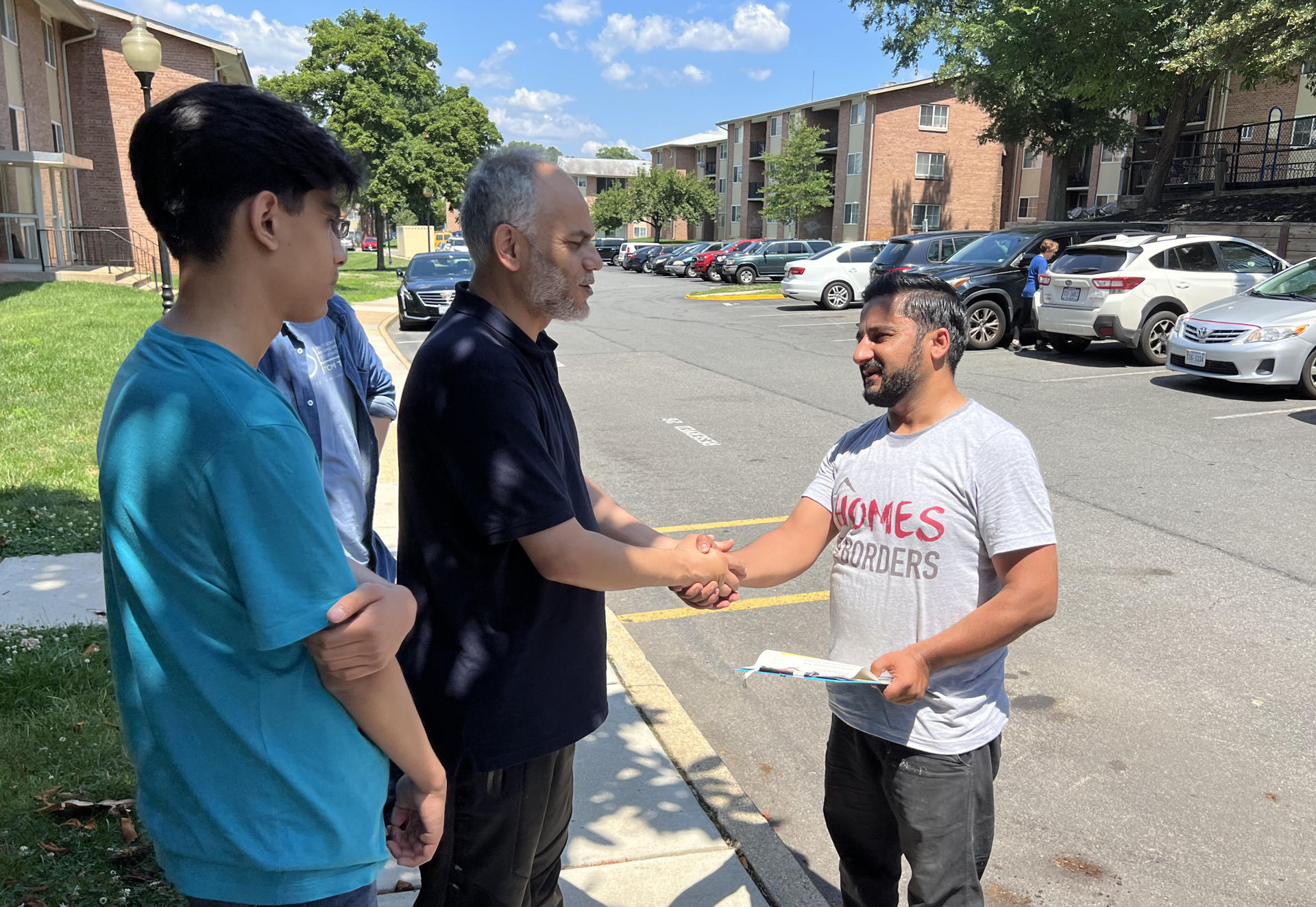 El afgano Nasser Haqparast (d), saluda a una familia de refugiados afganos a los que, junto a otros miembros del equipo de la ONG Homes Not Borders (Hogares No Fronteras), ayudó a amueblar su apartamento, el 11 de julio de 2023, en Arlington, Virginia (EE.UU.). EFE/ Eduard Ribas
