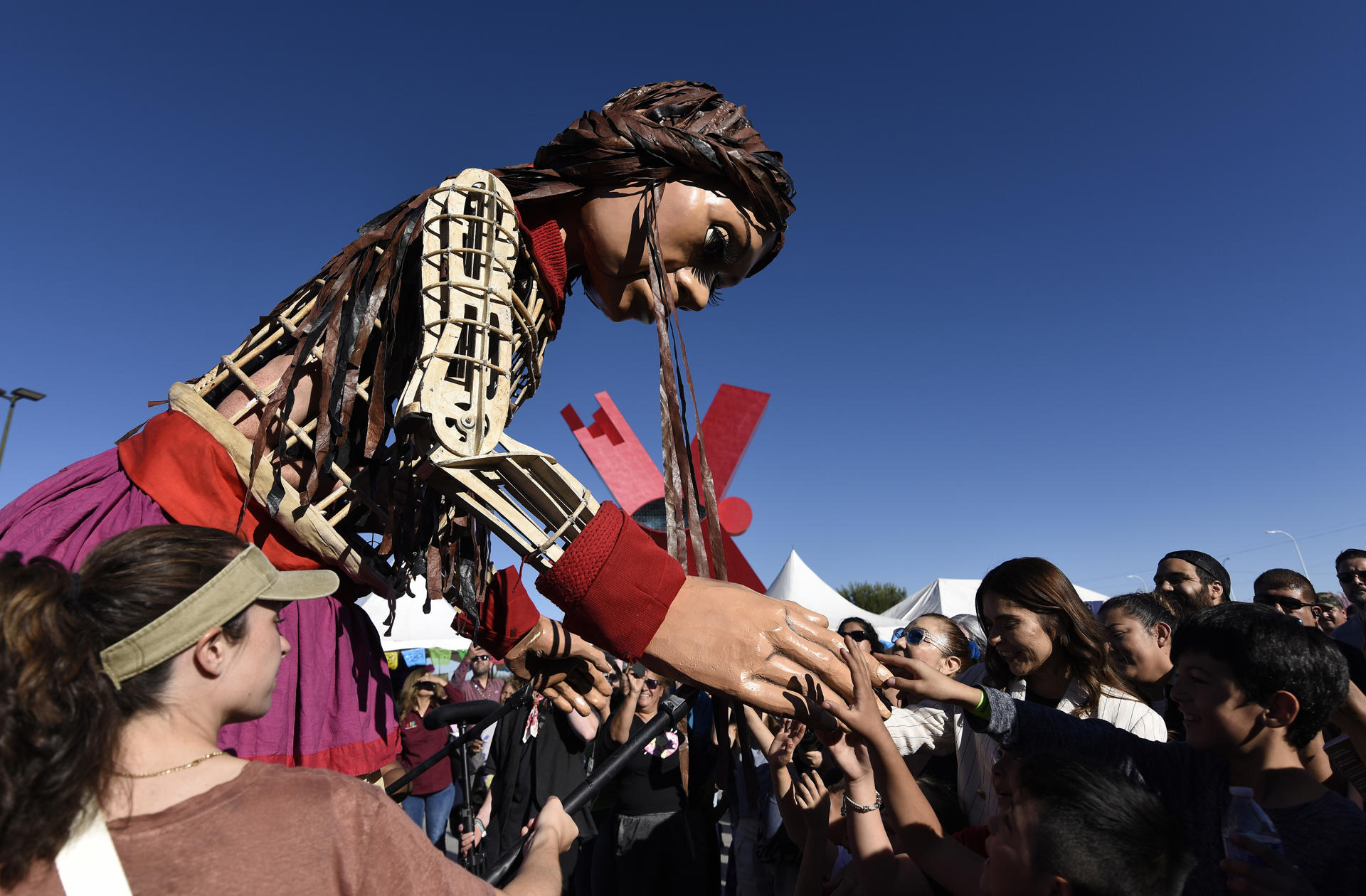 Personas observan el paso de "La Pequeña Amal", que representa a una niña siria durante un recorrido, el 26 de octubre de 2023, en Ciudad Juárez Chihuahua (México). EFE/Luis Torres.
