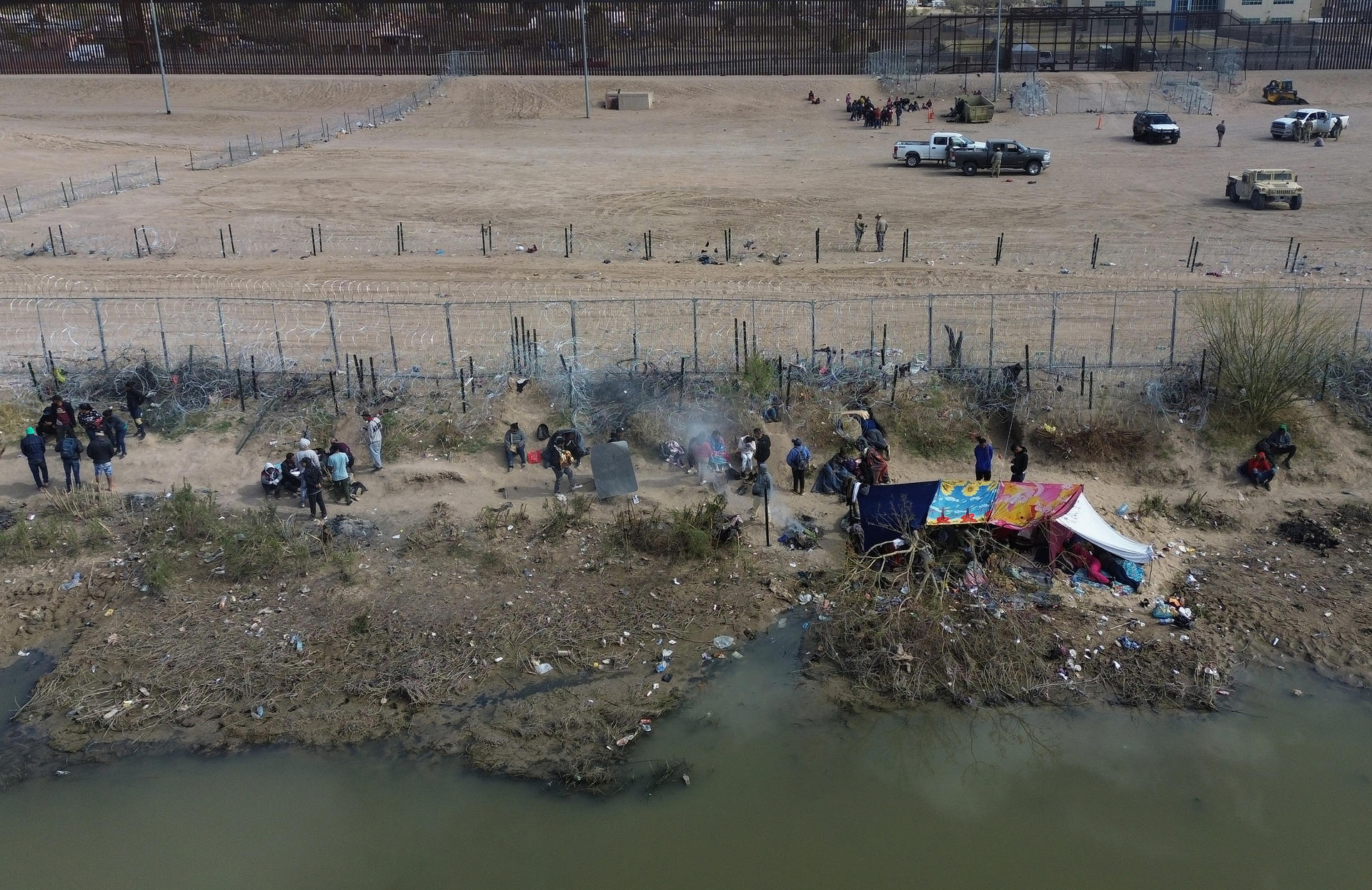 Fotografía aérea que muestra a migrantes en las inmediaciones del Río Bravo, junto al alambrado que divide a México con Estados Unidos, este miércoles, en Ciudad Juárez (México). EFE/ Luis Torres
