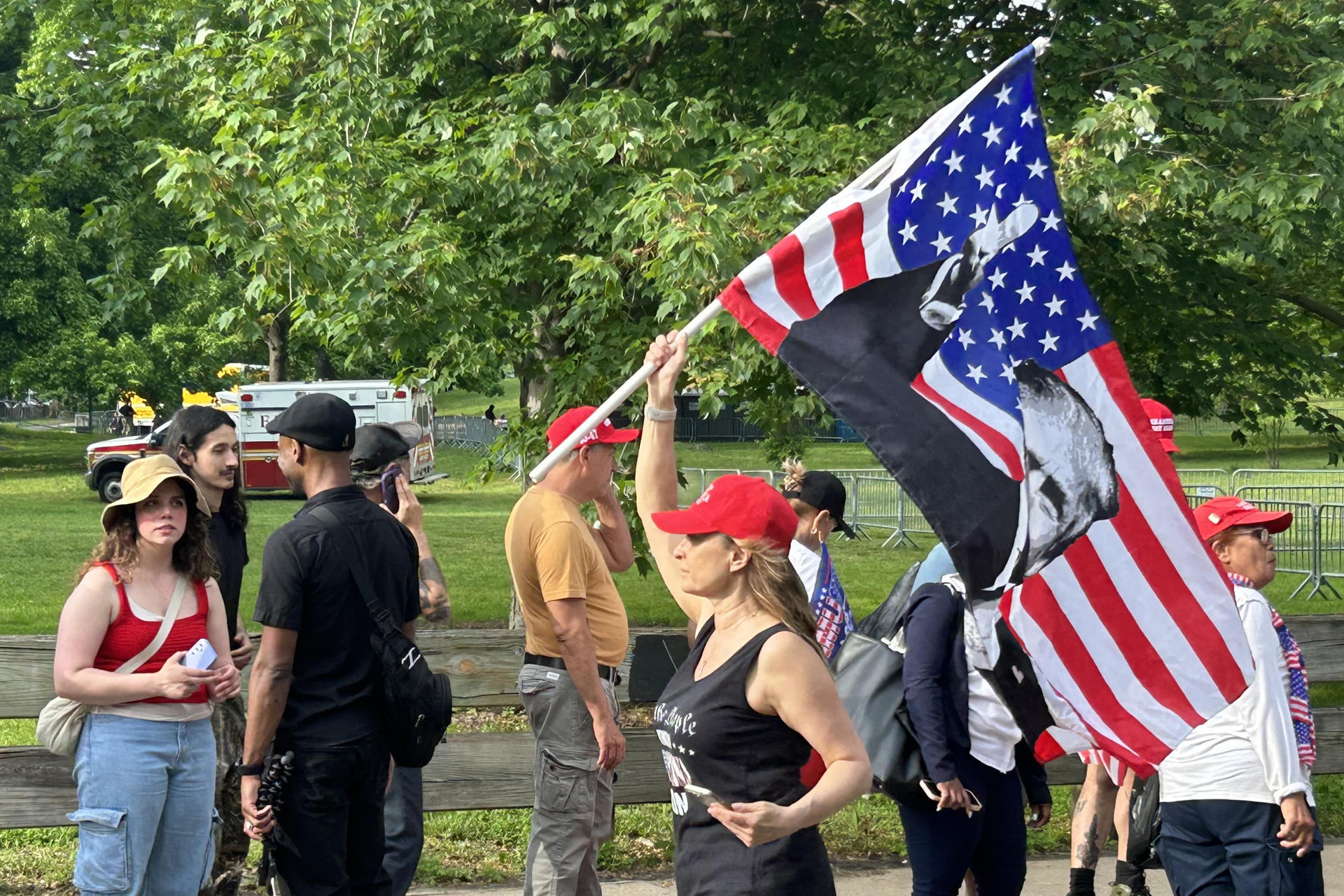 Una mujer carga una bandera de Estados Unidos con la imagen del expresidente de Estados Unidos Donald Trump durante un mitin este jueves, en Cotrona Park en Nueva York (EE. UU). EFE/ Javier Otazu Elcano
