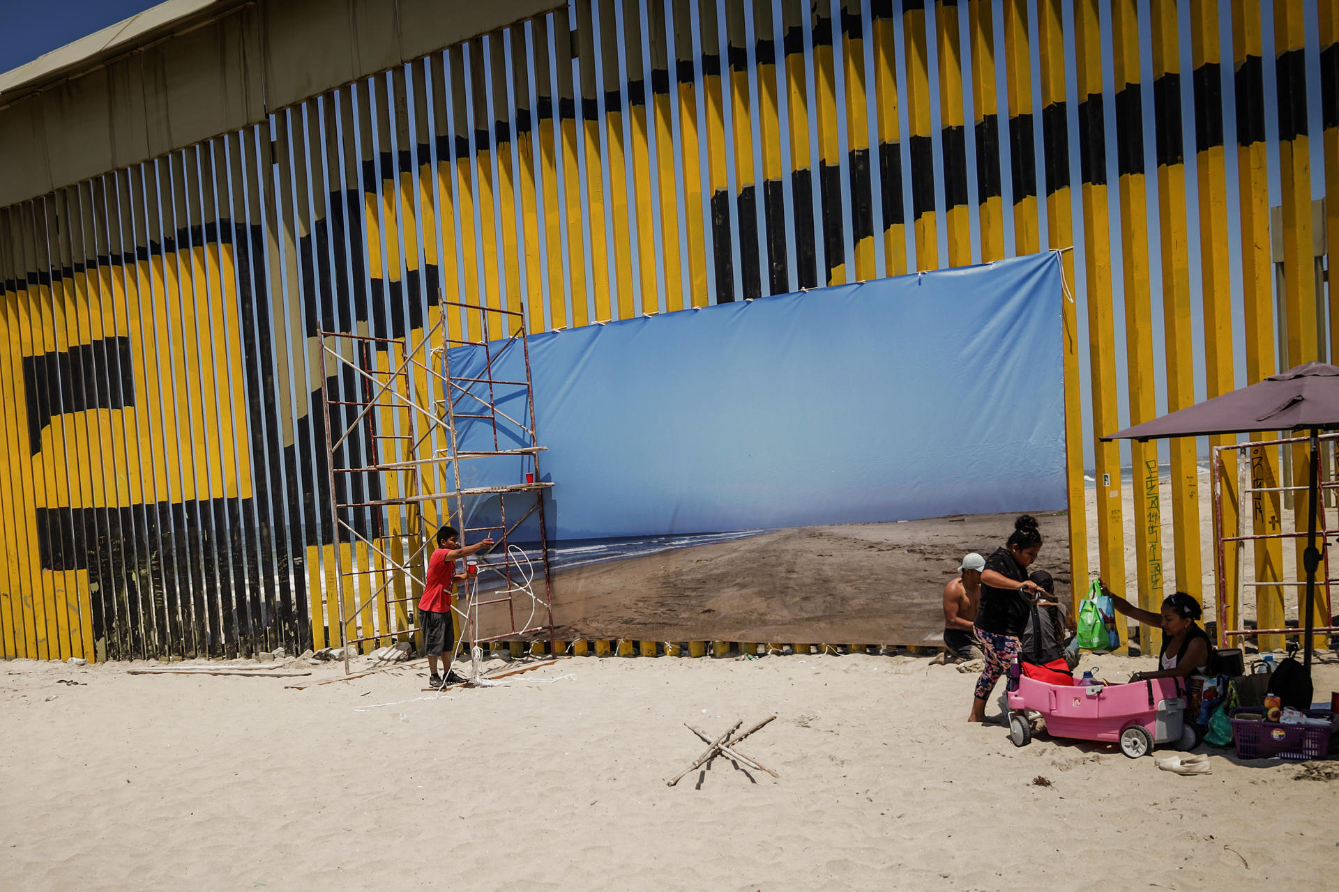 Una fotografía monumental es colocada en el muro fronterizo, el 26 de julio de 2024, en la ciudad de Tijuana, en Baja California (México). EFE/Joebeth Terríquez
