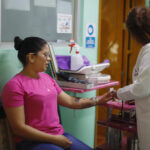 Fotografía del 16 de agosto del 2025 de la propietaria y médico en jefe de la clínica Unidad Médica Bassaury, Sarahí Hernández (d), atendiendo a Vanessa Alejo de origen venezolano en Ciudad Nezahualcoyotl (México). EFE/ Sáshenka Gutiérrez
