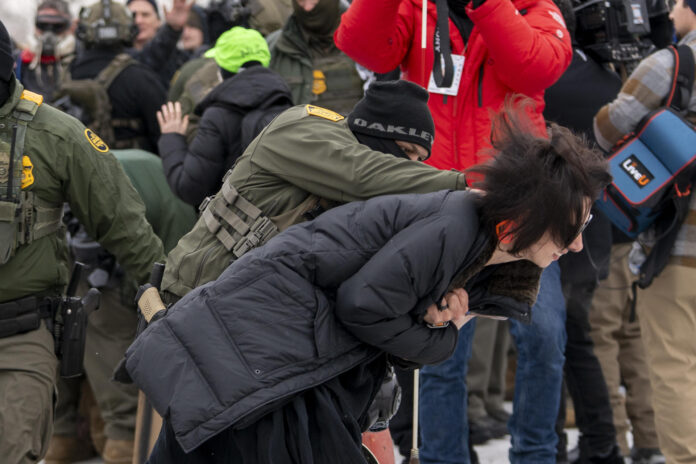 Un integrante de la Policía detiene a una persona durante las protestas frente al edificio Federal Bishop Henry este jueves, en Mineápolis (EE.UU.). EFE/ Angel Colmenares